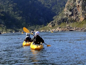 two people are kayaking down the snowy river which is one of the Kayaking Journeys NSW as on offer