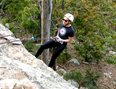 A man is abseiling down the twenty meter cliff on the Hunter Valley Abseiling Adventure