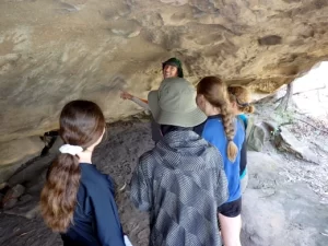 Girls are in a cave looking t indigenous paintings with an instructor during the Bronze Bushwalking Award