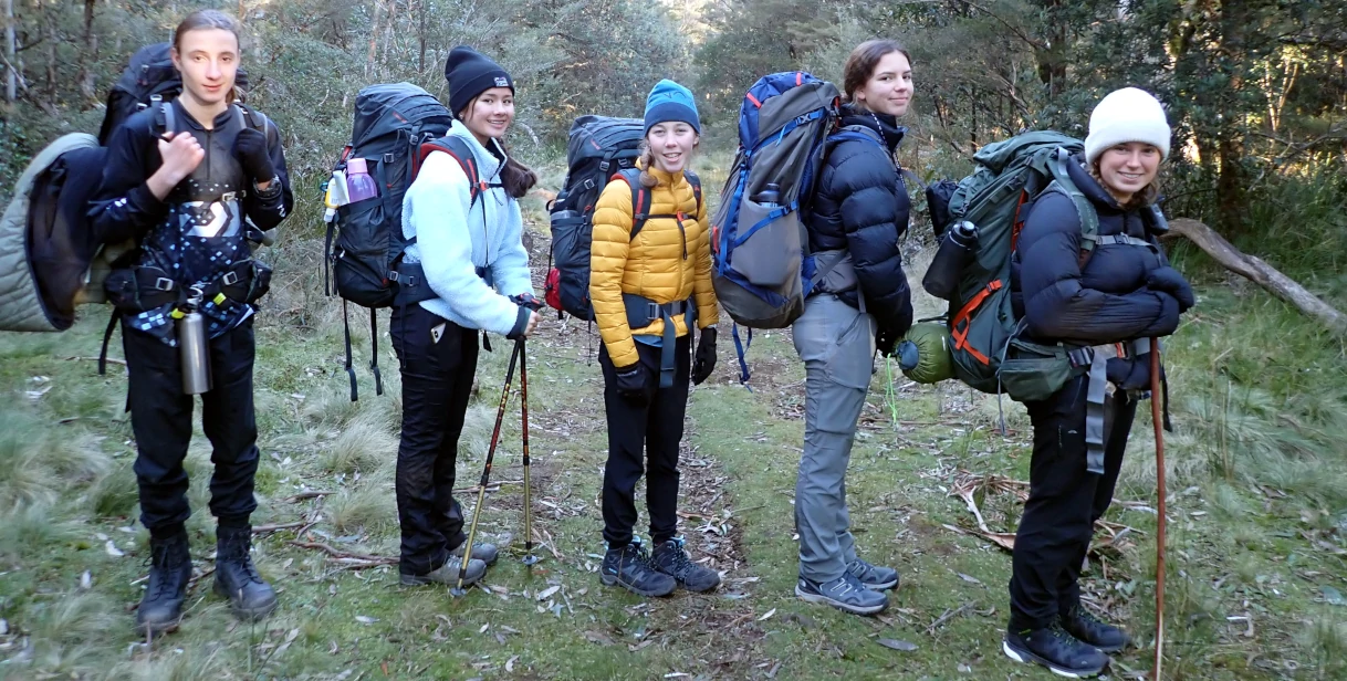 A group of hikers standing in a line looking into the camera