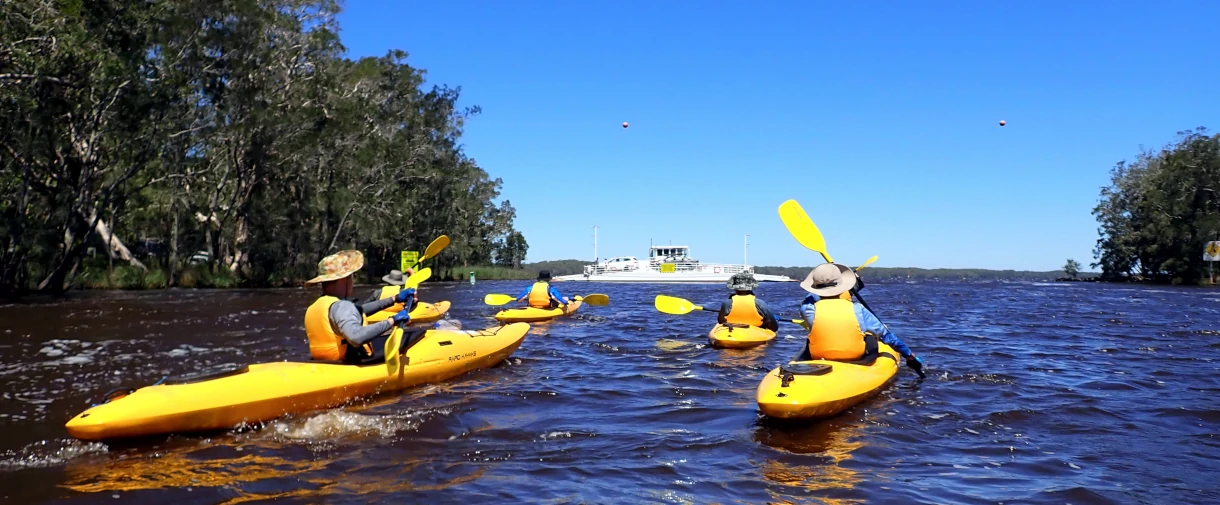 A group of Kayaks are paddling towards a ferry on the Bronze Kayaking Award Journey