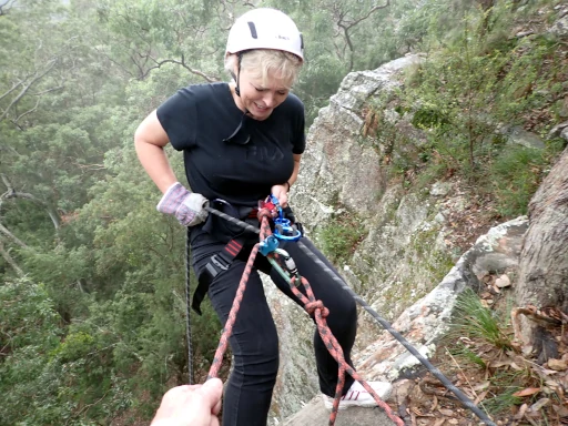 A abseiler is hunched over on top of the cliff very nervous on her first time at the Hunter Valley Abseiling Adventure