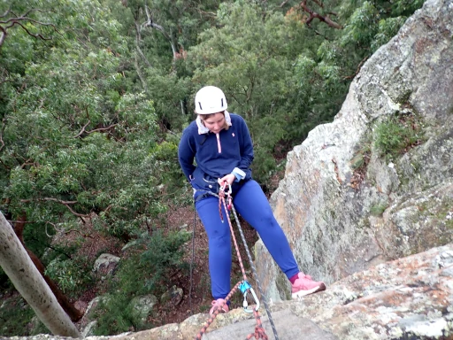 A young lady is abseiling down a cliff during the Hunter Valley Abseiling Adventure