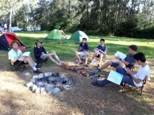 A group of students sitting relaxing around a fire pit on the Bronze Kayaking Award Journey