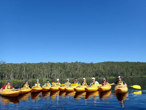 twelve kayakers are rafted together in a semi circle on one of walking rivers school programs