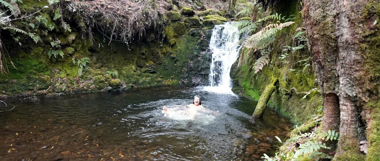 A person is swimming at the base af a waterfall on the Barrington Tops Bushwalking Adventure