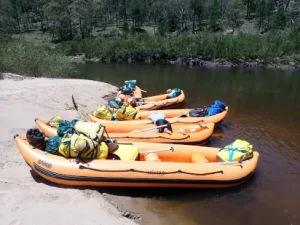Five rafts used during the Silver Rafting Award Journey are on the sandy riverbank with no people