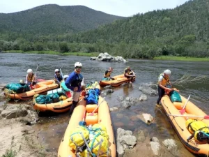 Silver Rafting Award Journey is shown here with people loading rafts on the river bank