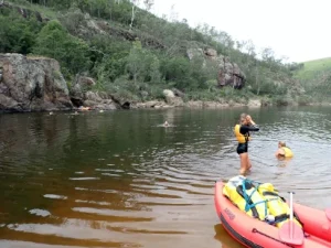 Duke of Edinburgh students are swimming withe the rafts on the riverbank during a Silver Rafting Award Journey