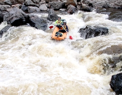 two people are paddling a raft deep in foaming water during the Snowy River whitewater rafting adventure.