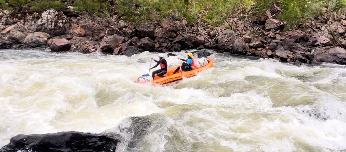 Two people are in a raft on a big rapid going down the Snowy River