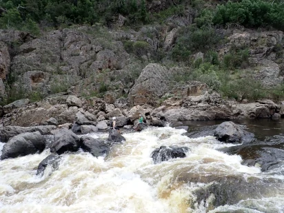 A person is standing on a rock in the middle of tulloch ard gorge snowy river