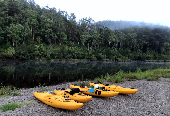 Kayaks on shore at a campsite Guided whitewater tour Kayaks on the shore of the Nymboida River NSW surrounded by rainforest.